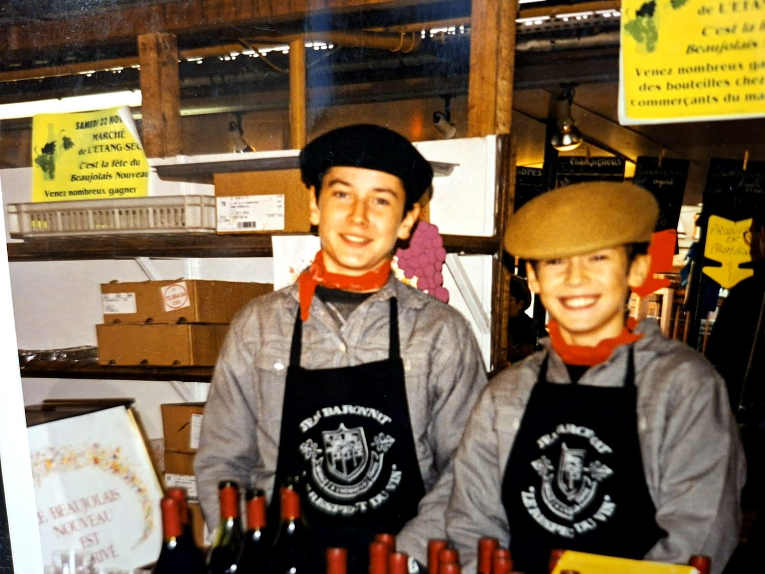 Deux jeunes garçons en tablier et béret derrière un étal, un jour de Beaujolais nouveau