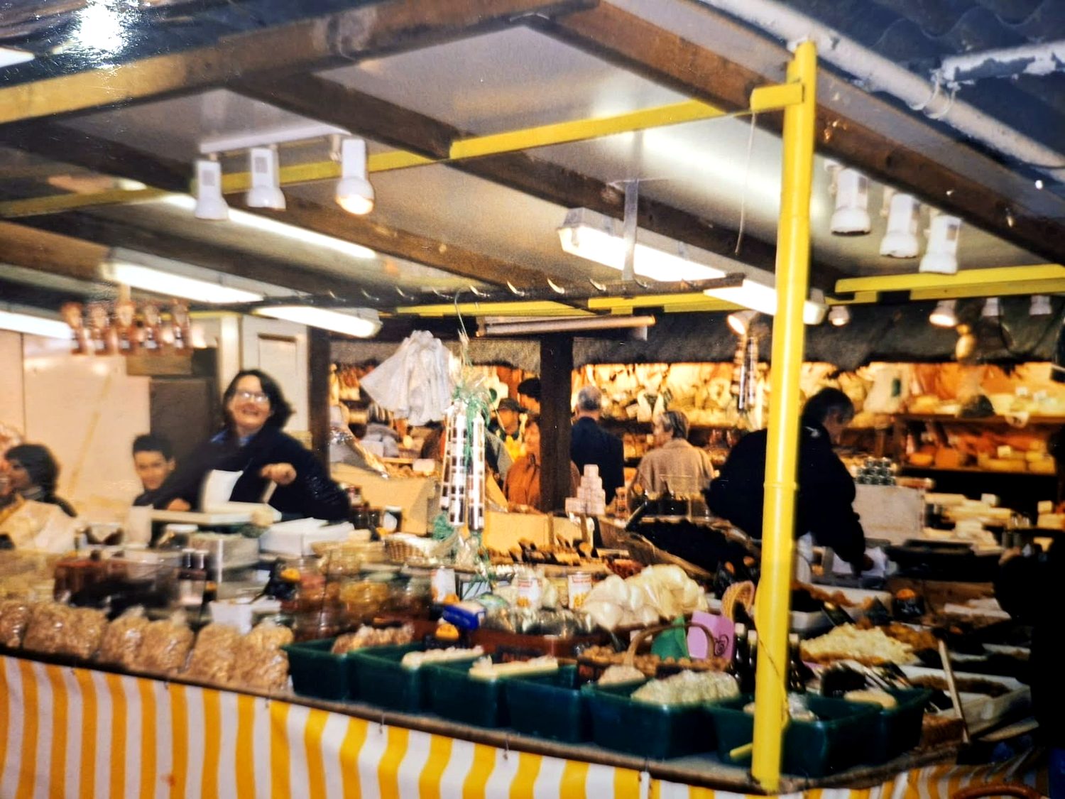 Étal foisonnant sous la halle du marché, clients et vendeurs affairés